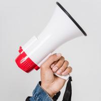 Fotografia de um braço segurando um megafone.